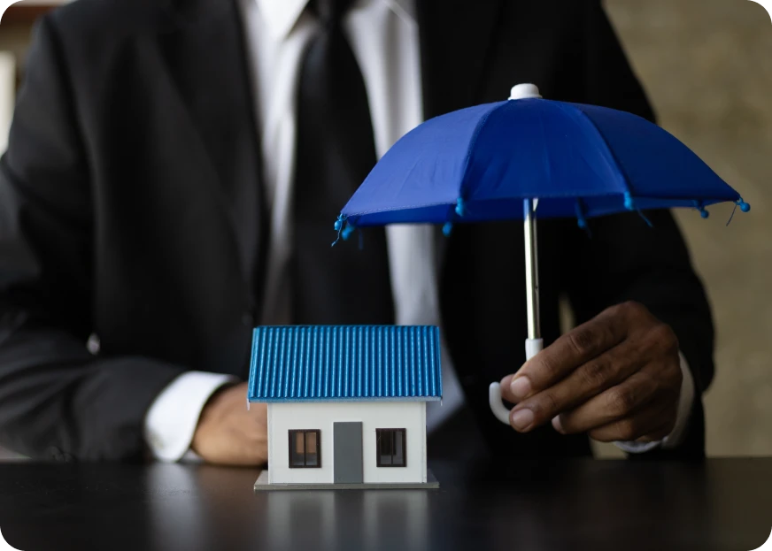 Person holding umbrella over house representing insurance protection and home coverage.